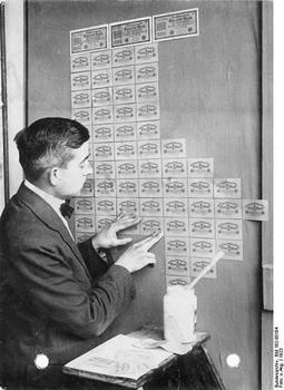 Mężczyzna tapetujący ścianę bezwartościowymi banknotami, 1923 r. 